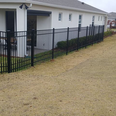 Black aluminium fence running along a street of new houses