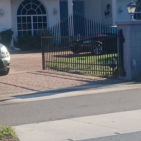Black aluminium fence in front of a house with a blue tile roof