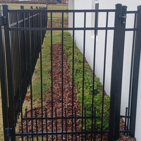 Black aluminium fence and gate at the corner of a house