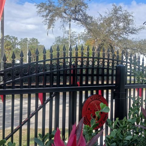 Black spear-top metal fence with flags flying behind it