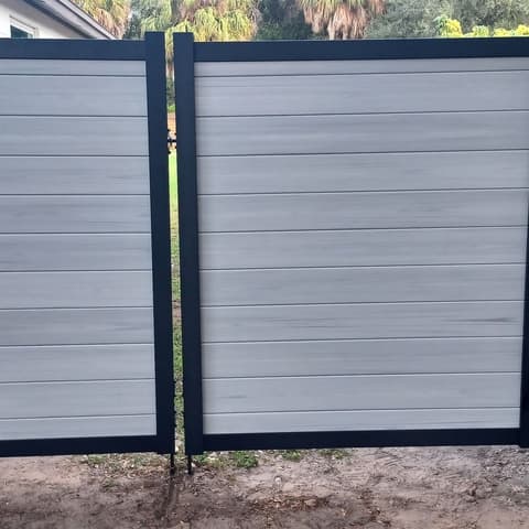 Grey composite double gate in a black steel frame, filling the frame