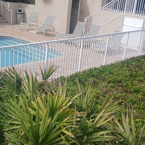 White aluminium pool barrier fence around a screened pool deck