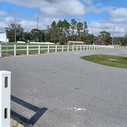 White vinyl ranch rail fence following the curve of a road