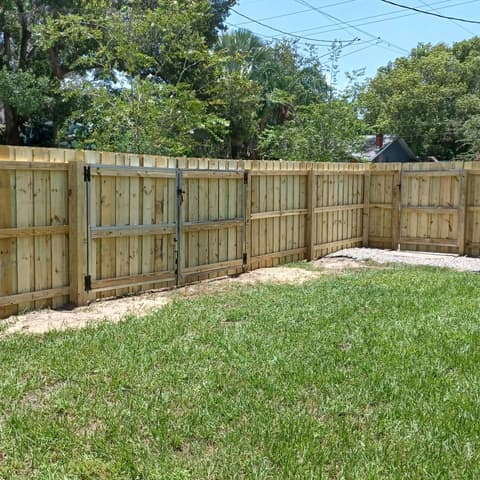 Finished wood privacy fence and gate over a green lawn