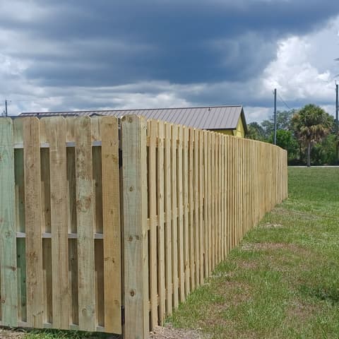 Wood shadowbox fence and gate beside a shed under a big sky